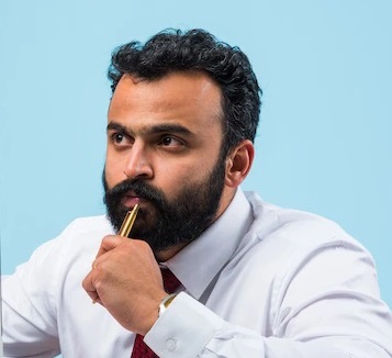 portrait-young-indian-businessman-beard-sitting-relaxed-position-office-table-with-pleasant-look-confident-asian-male-business-person_466689-15526